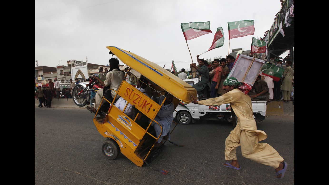 A supporter of Pakistani politician Imran Khan runs to catch an overloaded rickshaw as he and others join <a href="http://www.cnn.com/2014/08/15/world/asia/pakistan-khan-qadri-march/index.html">an anti-government rally</a> in Gujrat, Pakistan, on Friday, August 15.