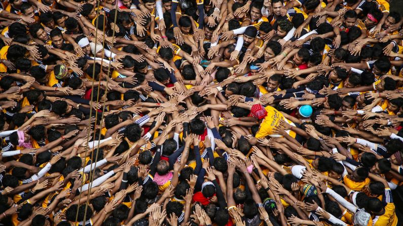 During the Janmashtami Festival, which celebrates the birth of Hindu god Lord Krishna, devotees in Mumbai, India, pray before forming a human pyramid to reach and break an earthen pot suspended high above the ground on Monday, August 18.