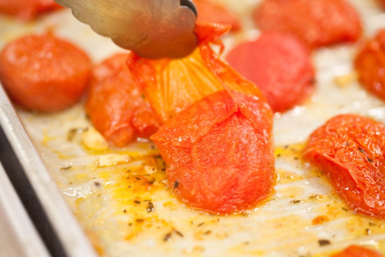 Use tongs to remove and discard the hot tomato skins, and then return the tomatoes to the oven. After 1 hour (be sure to keep siphoning off any remaining liquid), use a spatula to flip the tomato pieces cut-side up for the remainder of cooking.