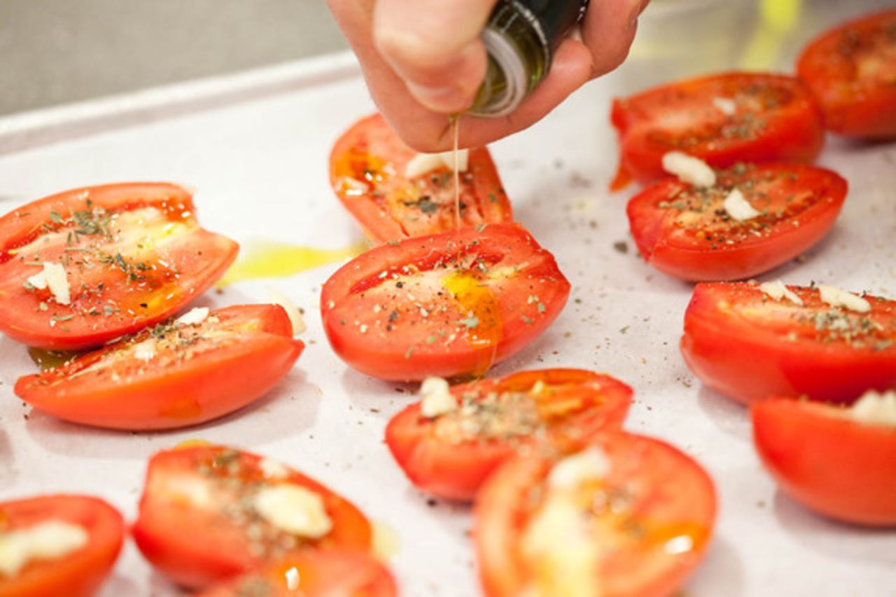 Drizzle olive oil over the tomatoes with your thumb over the spout to direct the pour.