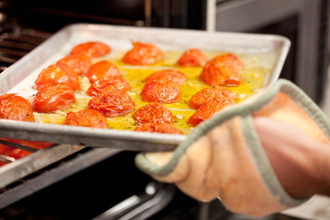 Carefully remove the tomatoes from the oven, and immediately turn the temperature down to 300 degrees. The tomatoes will have started giving up their liquid, which is why caution must be exercised when removing the trays.