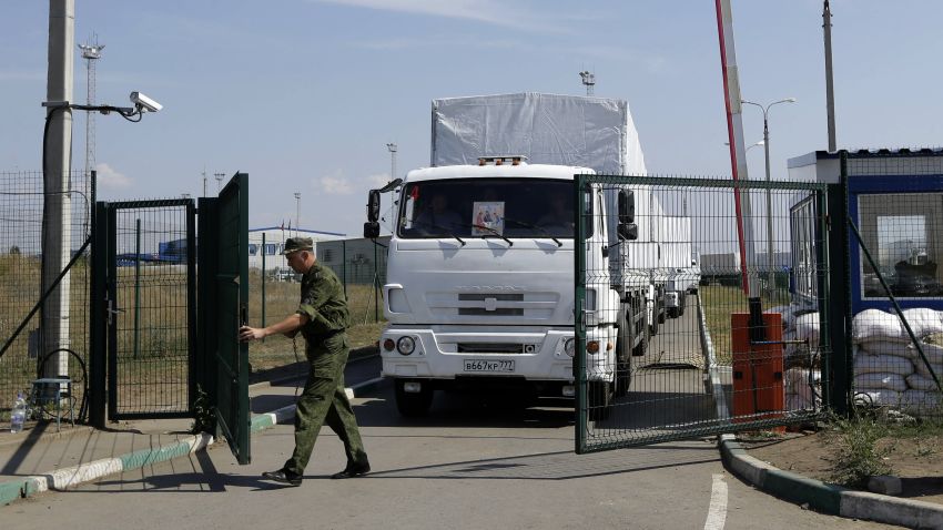 A Russian border guard opens a gate into the Ukraine for the first trucks heading into the country from the Russian town of Donetsk, Rostov-on-Don region, Russia, Friday, Aug. 22, 2014. The first trucks in a Russian aid convoy crossed into eastern Ukraine on Friday, seemingly without Kiev's approval, after more than a week's delay amid suspicions the mission was being used as a cover for an invasion by Moscow.(AP Photo/Sergei Grits)