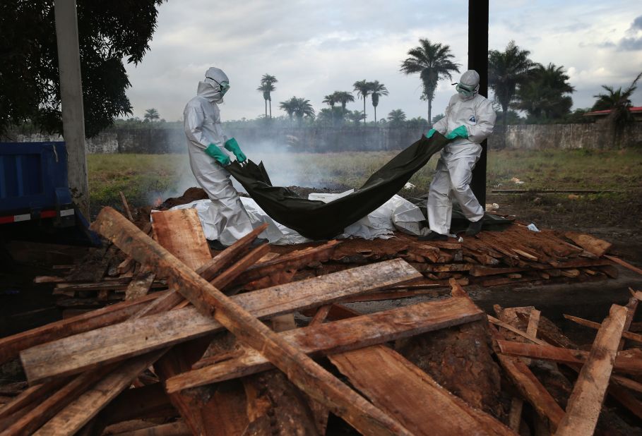 A burial team from the Liberian Ministry of Health unloads bodies of Ebola victims onto a funeral pyre at a crematorium in Marshall, Liberia, on August 22, 2014.