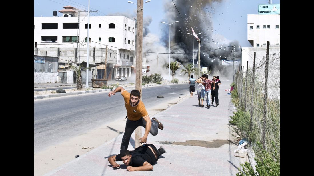 Palestinians run away from debris after a bomb from an Israeli airstrike hit a house in Gaza on Saturday, August 23.