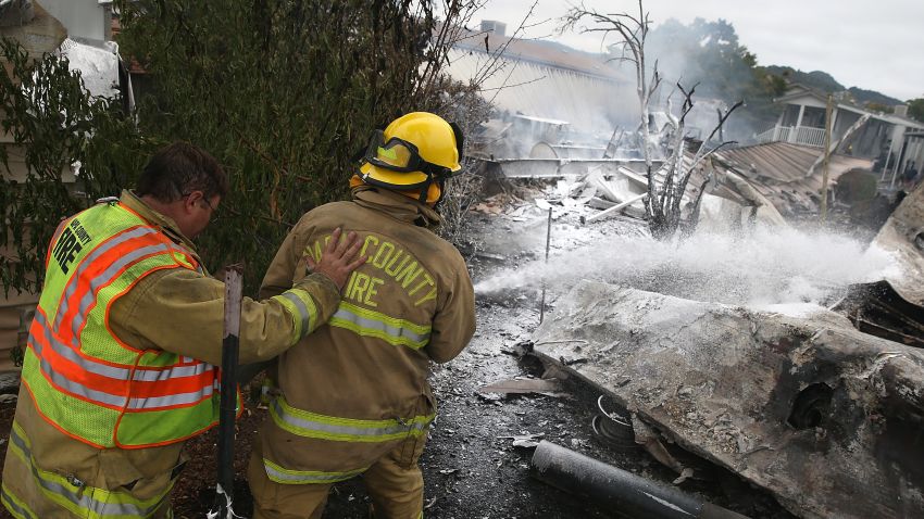 Napa County firefighters spray foam on hot spots from a fire at a mobile home park after an earthquake Sunday.