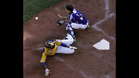 Chicago's Trey Hondras, in yellow, scores past South Korea's Sang Hoon-han on a two-run double by Darion Radcliff during the sixth inning on August 24. 