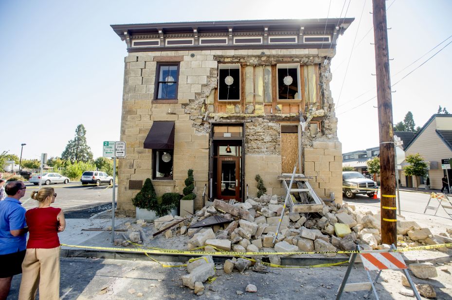 Pedestrians stop to examine a crumbling facade at the Vintner's Collective tasting room in Napa on August 24.