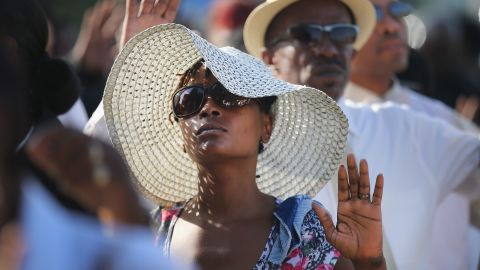 Funeral attendees raise their hands as they wait in line to enter the church on August 25.