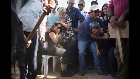 Gila, center, mother of 4-year-old Israeli boy Daniel Tragerman, sits next to his grave during his funeral near the Israel-Gaza border on Sunday, August 24.