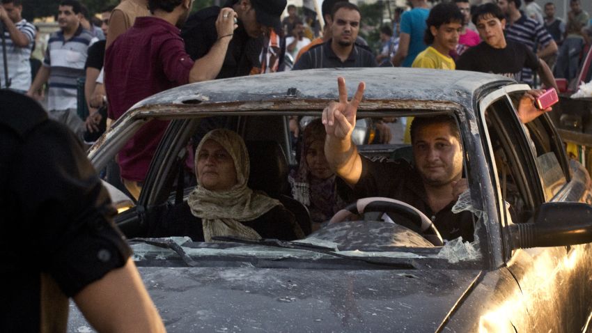 A Palestinian man flash the sign of victory through the shatered front window of his battered car as he makes his way through an intersection in Gaza City where people gather to celebrate the ceasefire between Israel and Hamas on August 26, 2014. Egypt said that a Gaza ceasefire that went into force at 1600 GMT provides for an immediate opening of Israeli border crossings to aid and reconstruction supplies. AFP PHOTO/ROBERTO SCHMIDT (Photo credit should read ROBERTO SCHMIDT/AFP/Getty Images)