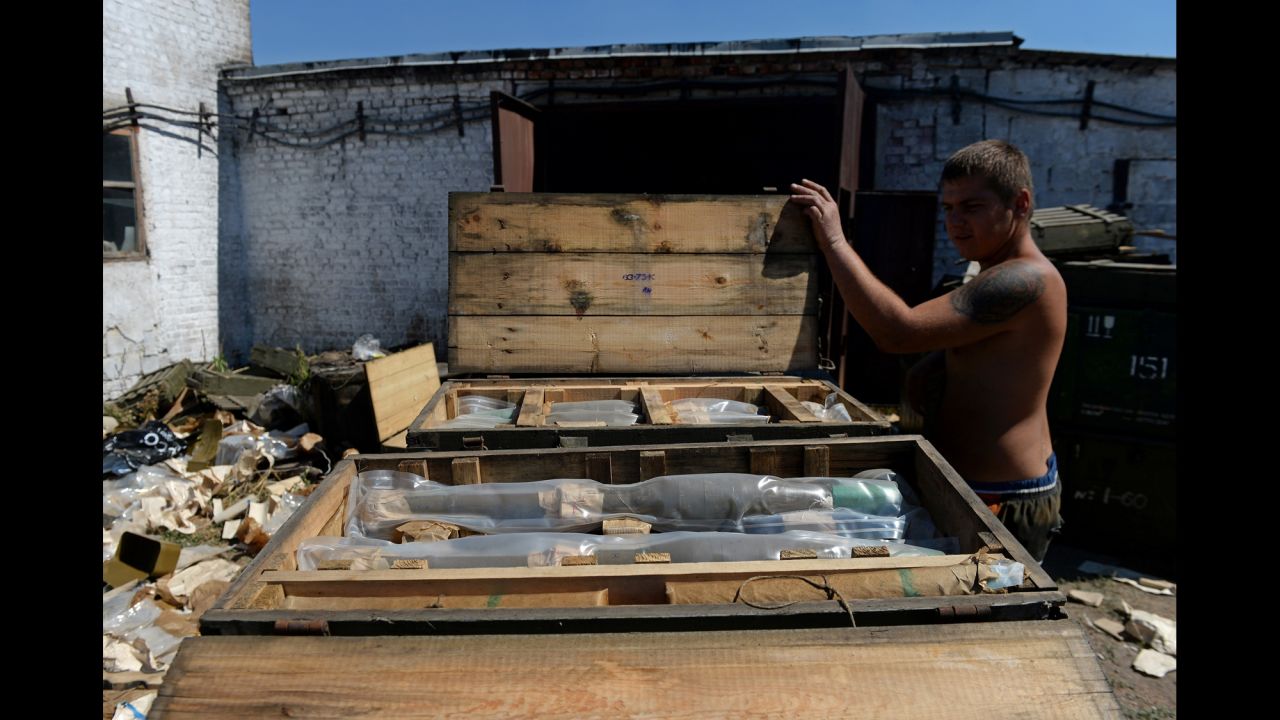 A man opens a box filled with rocket-propelled grenades left by the Ukrainian army in Starobesheve.