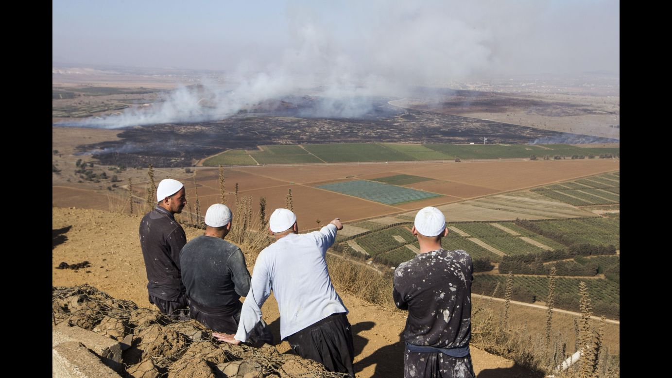 Druze men watch from the Golan Heights side of the Quneitra border with Syria as smoke rises during fighting between rebels and forces loyal to al-Assad on Wednesday, August 27. 
