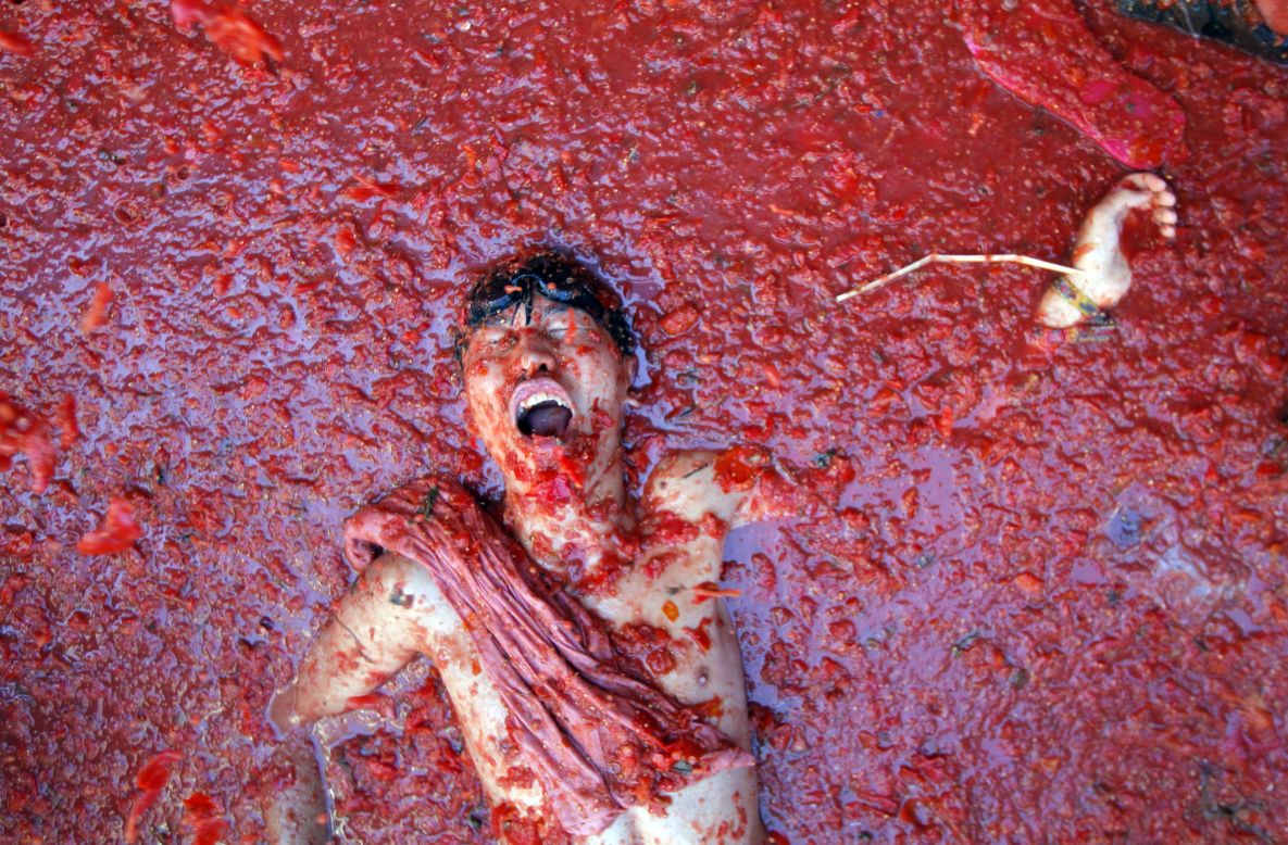 AUGUST 28 - BUNOLA, SPAIN: A man lies in a puddle of squashed tomatoes, during the annual "tomatina" tomato fight fiesta. The streets of the eastern Spanish town of Bunola are awash with red pulp as around 22,000 people pelt each other with 125 tons of ripe tomatoes.
