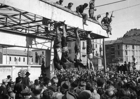 The bodies of Benito Mussolini, left, and his mistress, Clara Petacci, second from left, hang from the roof of a gasoline station after they were shot by anti-Fascist forces while attempting to escape to Switzerland on April 28, 1945.