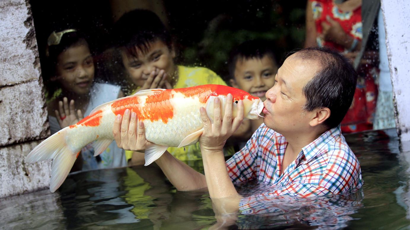 Zoo owner Manny Tangco kisses a Japanese Koi carp while children watch on Friday, August 22, in Malabon, a city north of Manila in the Philippines.