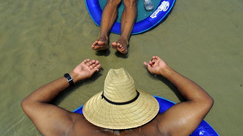 Ron Mcgee, bottom, and Shawn Williams sunbathe in a shallow tidal pool in Tybee Island, Georgia, on Saturday, August 23.