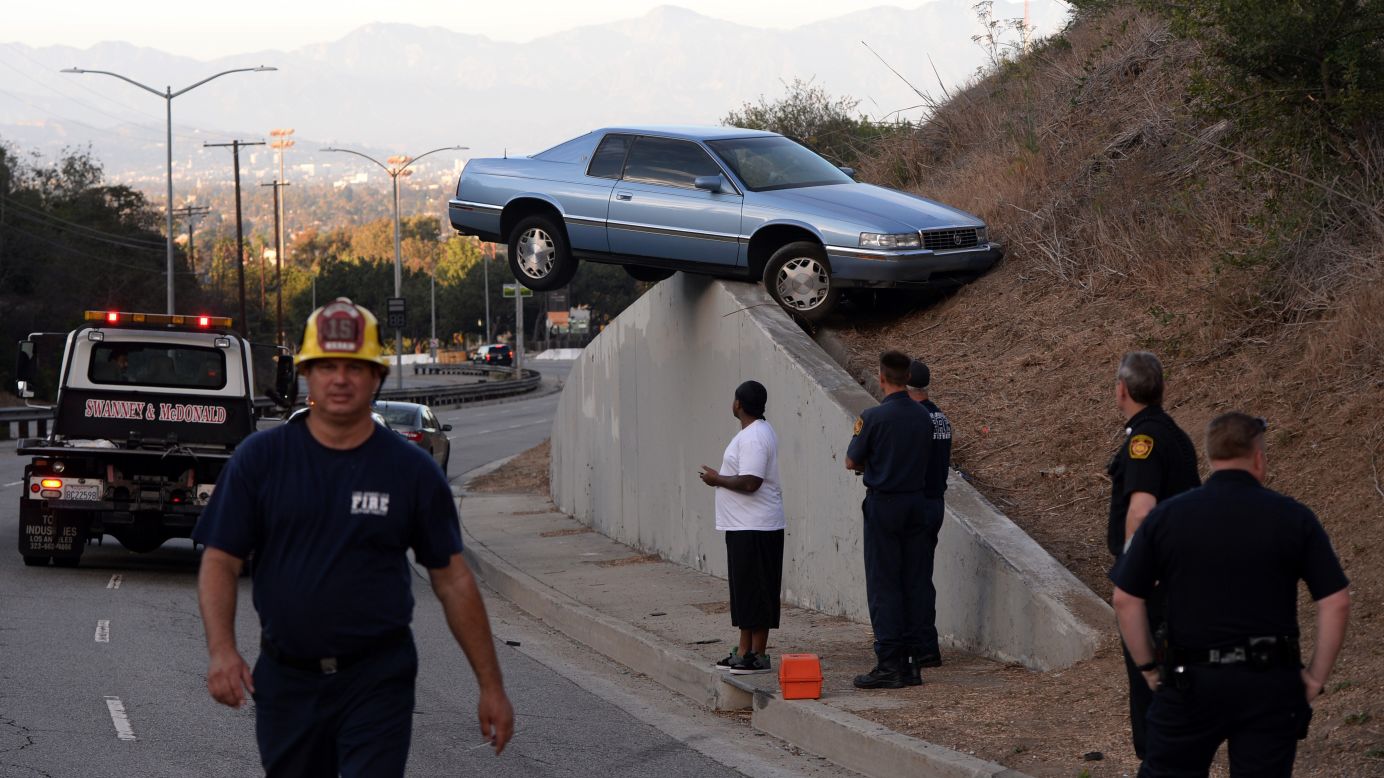 A car sits atop an embankment after its driver lost control and skidded up the concrete retaining wall in Los Angeles on Sunday, August 24. The driver and his passenger escaped injury.