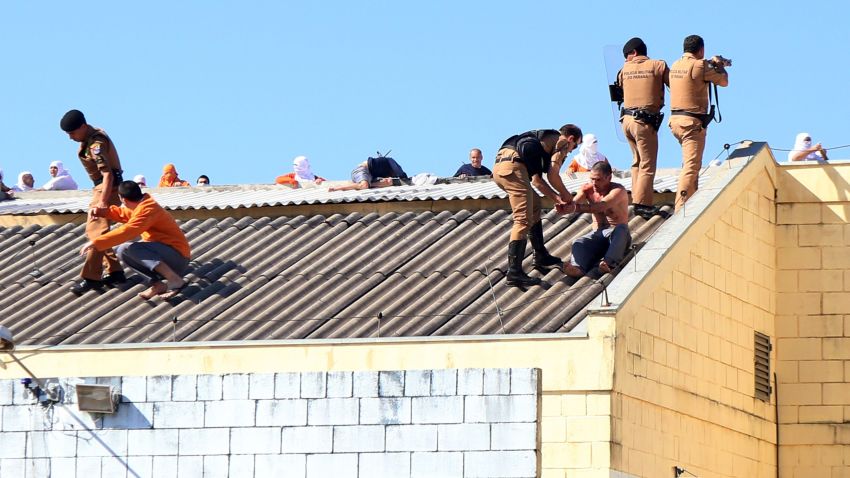 Security forces storm the roof of the penitentiary where inmates were gathering in Cascavel, Parana state, Brazil, on August 25, 2014. Inmates rioting for better facilities in a Brazilian jail killed four fellow prisoners, decapitating two of them, and took two guards hostage, officials said Sunday.