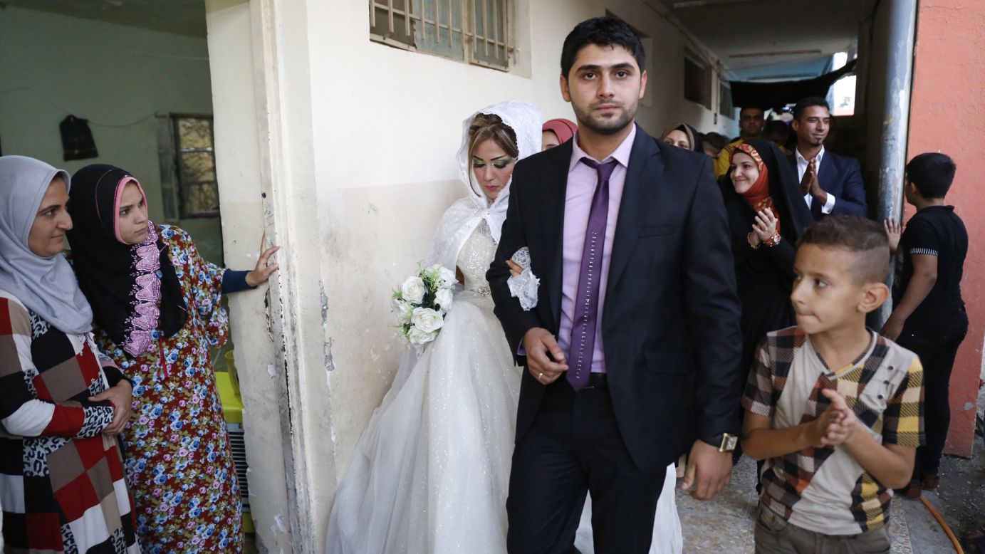 Mohammed Harith Youssif, a displaced Iraqi Shiite, walks with his Sunni bride, Reem Ahmed, during their wedding Monday, September 1, at a school in Baghdad. The couple fled to Baghdad after the militant group ISIS advanced into their hometown of Mosul, Iraq.