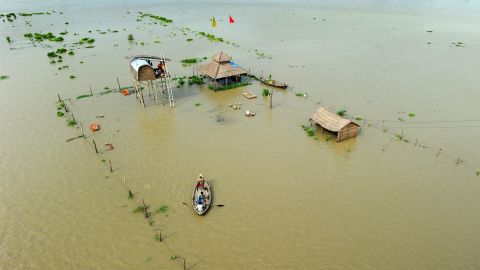 People flee submerged huts on the flooded banks of the Ganga on Friday, August 8.