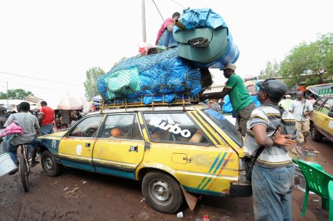 After an Ebola case was confirmed in Senegal, people load cars with household items as they prepare to cross into Guinea from the border town of Diaobe, Senegal, on September 3, 2014.