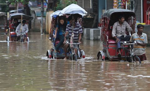 Rickshaw drivers transport commuters through floodwaters September 5 in Gauhati, India.