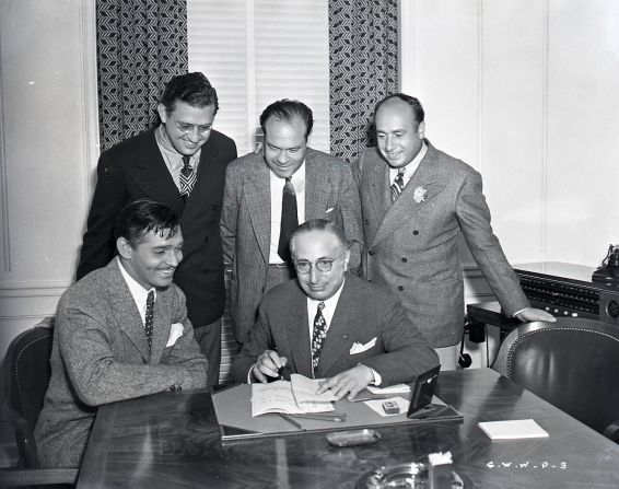 For publicity purposes, Clark Gable, the overwhelming popular choice to play Rhett Butler, pretends to sign a contract for the film under the watchful eye of producer Selznick, standing, far left, and MGM studio chief Louis B. Mayer, seated right. The star had been reluctant to tackle the role, fearing he wouldn't be able to live up to the public's expectations. With Gable now available, Selznick had to move quickly to start filming.