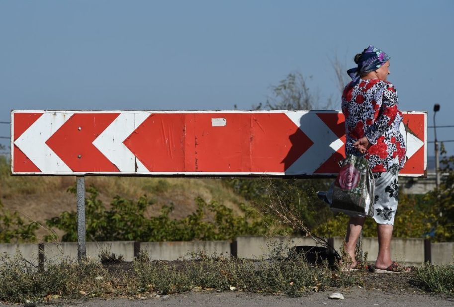 A woman stands next to a road sign September 7 after an overnight bombing attack at an Ukrainian army checkpoint on the outskirts of Mariupol. 
