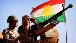 caption:A flag of the autonomous Kurdistan region flies next to Iraqi Kurdish Peshmerga fighters standing on a tank as they hold a position on the front line in Khazer, near the Kurdish checkpoint of Aski kalak, 40 km West of Arbil, the capital of the autonomous Kurdish region of northern Iraq, on September 7, 2014. Kurdish forces in the north have been bolstered by American strikes and recently took control of Mount Zardak, a strategic site east of Mosul that provides a commanding view of the surrounding area, a senior officer said. AFP PHOTO / SAFIN HAMED (Photo credit should read SAFIN
