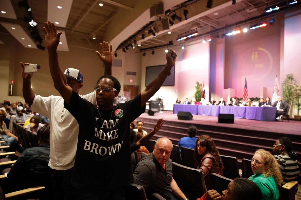 Marurice Brown raises his arms during the public comments portion of the meeting.