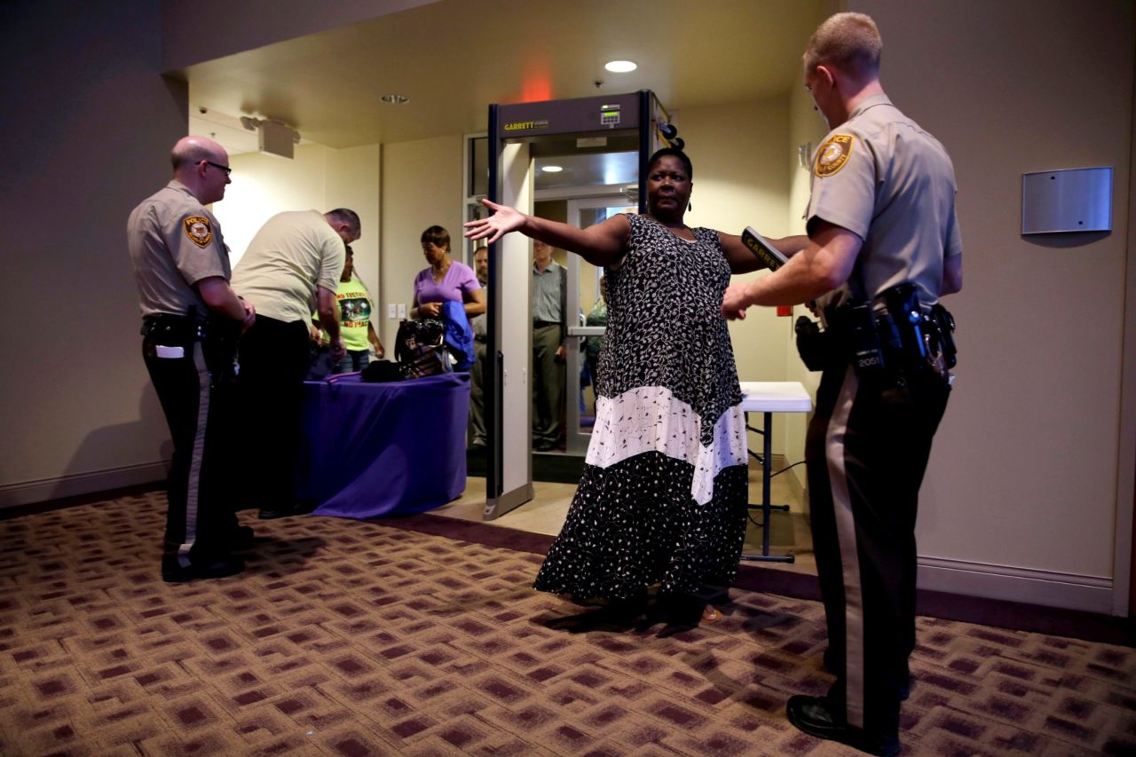 Patricia Cowan holds out her arms for a St. Louis County police officer as she and others are searched as they enter Greater Grace Church before the start of the meeting.