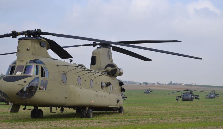 The helicopters wait in the field.