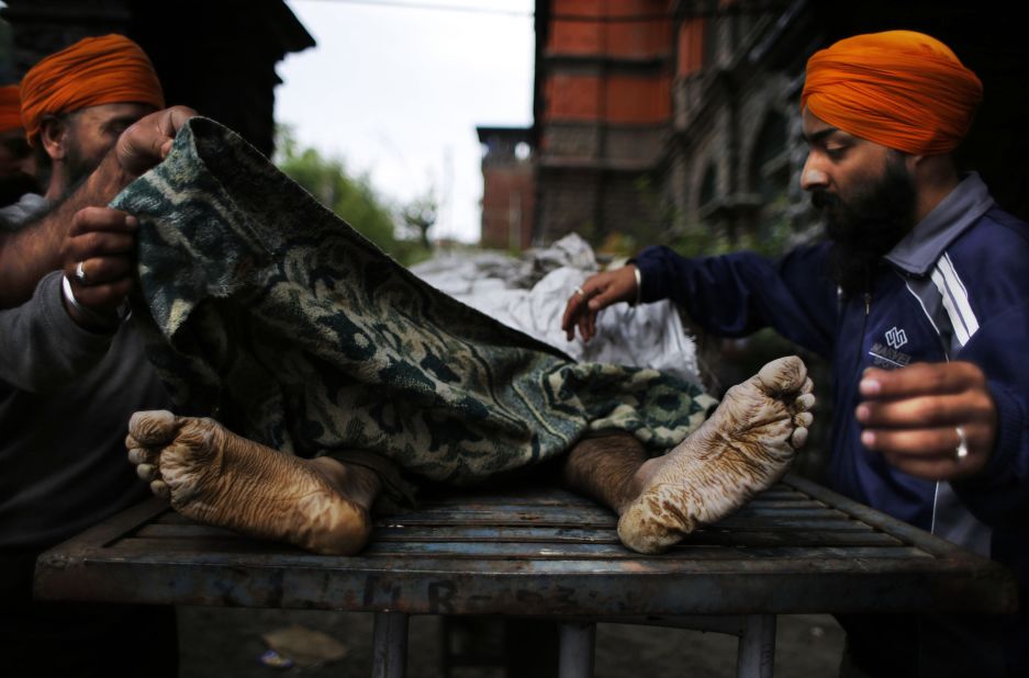 Kashmiri Sikhs cover the body of an Indian businessman whose body was fished out from floodwaters in Srinagar on September 12. 