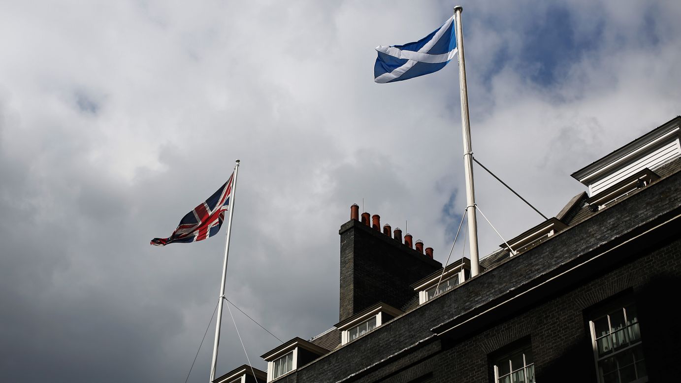 The national flag of the United Kingdom, left, and the national flag of Scotland fly above buildings on Downing Street in London.
