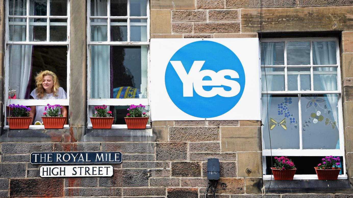 A woman looks from a window next to a "yes" campaign sign in Edinburgh on Tuesday, September 9.