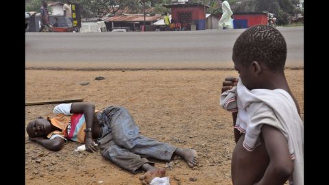 A child stops on a Monrovia street September 12, 2014, to look at a man who is suspected of suffering from Ebola.