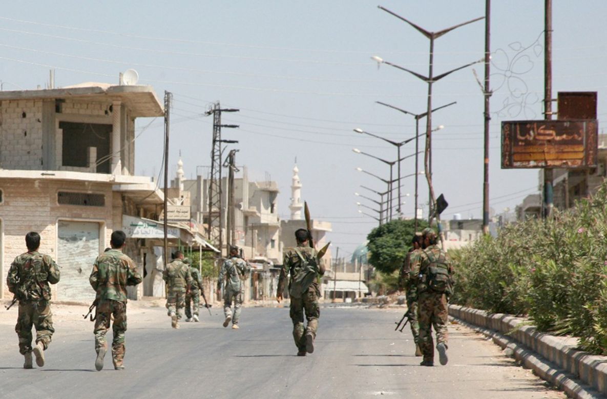 Syrian government forces walk down a street in Halfaya, Syria, after taking the city from rebel forces on Friday, September 12. 
