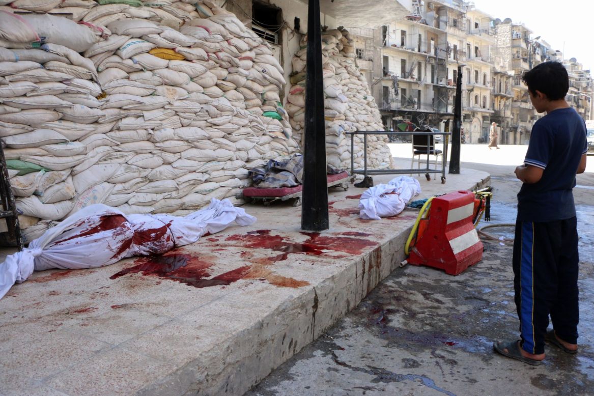 A boy looks at bodies lying outside a hospital after a barrel-bomb attack in Aleppo on Friday, September 5.
