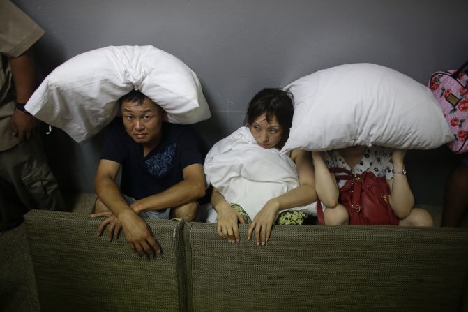 A family from San Jose, California, covers themselves with pillows as they sit in the service area of a Los Cabos resort on September 15.