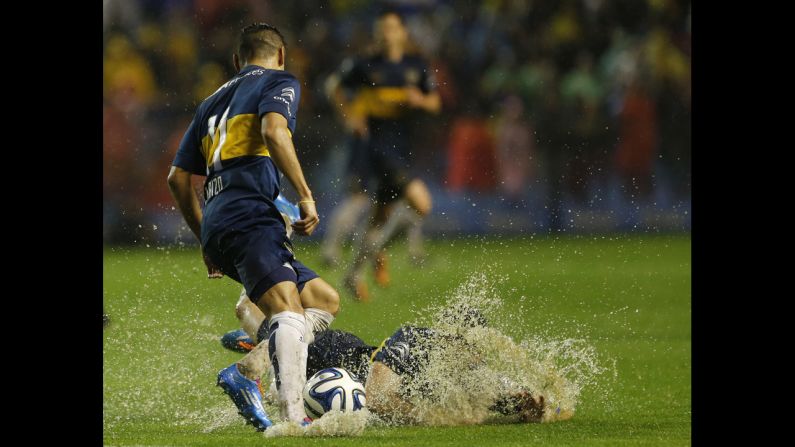 Jonathan Calleri of Argentine soccer club Boca Juniors falls down next to teammate Federico Carrizo during a match against Racing Club on Sunday, September 14. The match in Buenos Aires was postponed shortly after halftime because the field was too soaked by rain.