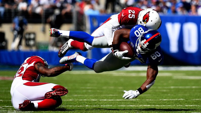 New York Giants wide receiver Victor Cruz is tackled by Arizona Cardinals cornerback Jerraud Powers during an NFL game Sunday, September 14, in East Rutherford, New Jersey. The Cardinals defeated the Giants 25-14 to stay undefeated through two games.