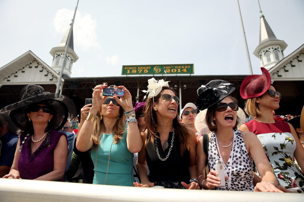 Race fans wearing festive hats cheer prior to the 140th running of the Kentucky Derby at Churchill Downs on May 3, 2014 in Louisville, Kentucky. 