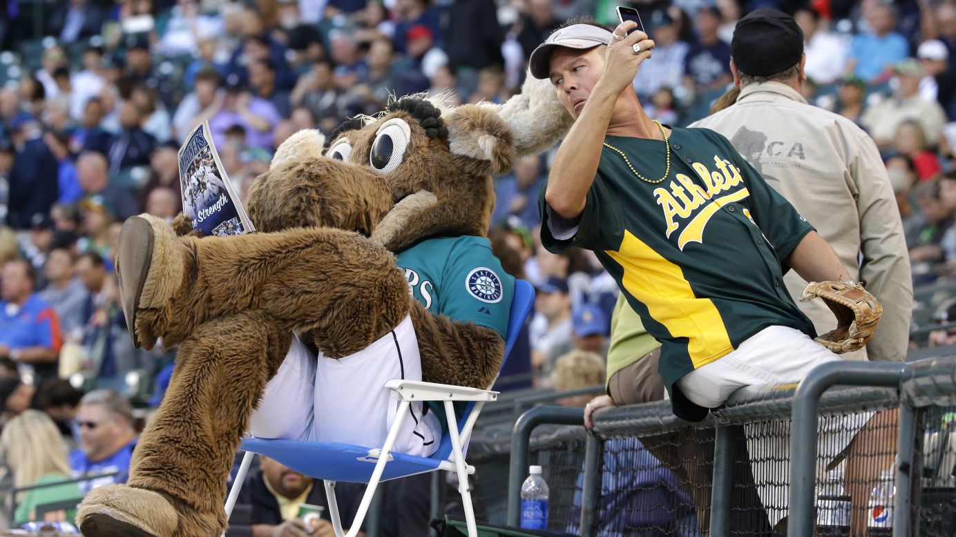 An Oakland Athletics fan tries to take a selfie with the Mariner Moose, the Seattle Mariners' mascot, before a Major League Baseball game Friday, September 12, in Seattle.