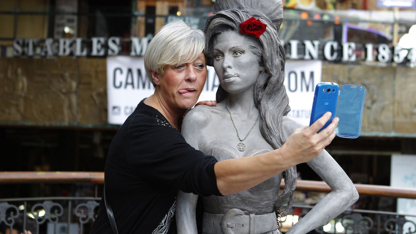 A woman takes a selfie with a new statue of the late singer Amy Winehouse on Monday, September 15, in London. Winehouse would have been 31 on September 14.