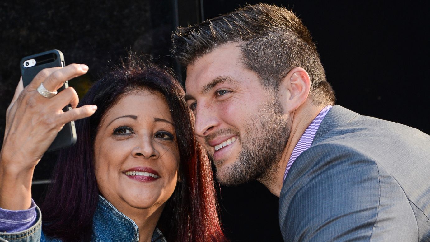 Tim Tebow, the former football player who is now a television personality, smiles for a fan's photo as he leaves a "Good Morning America" taping Monday, September 15, in New York.