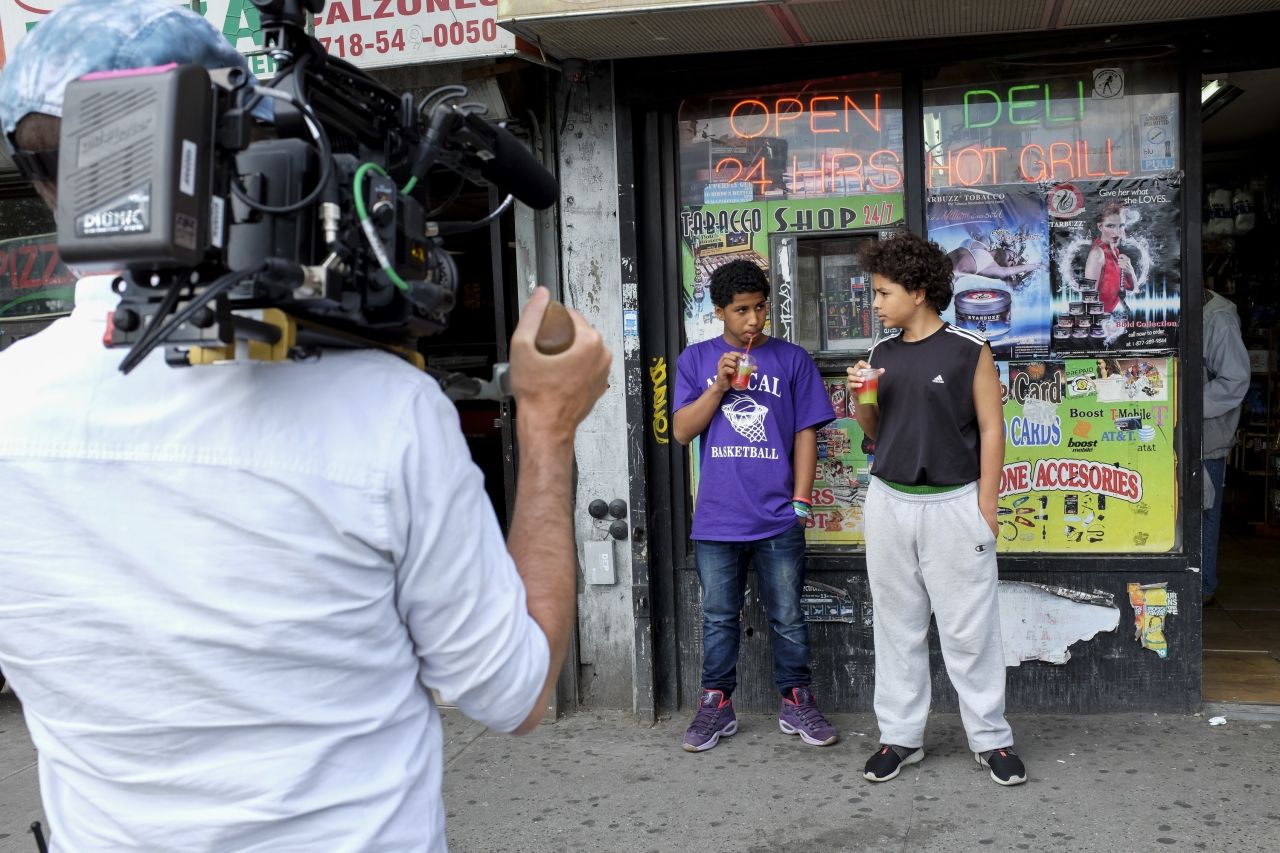 A couple kids from the neighborhood sip on drinks outside the local bodega.