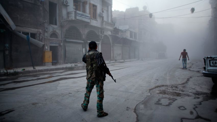 A rebel fighter stands on a street covered with dust following a reported air strike by Syrian government forces in the old city of Aleppo on July 21, 2014.