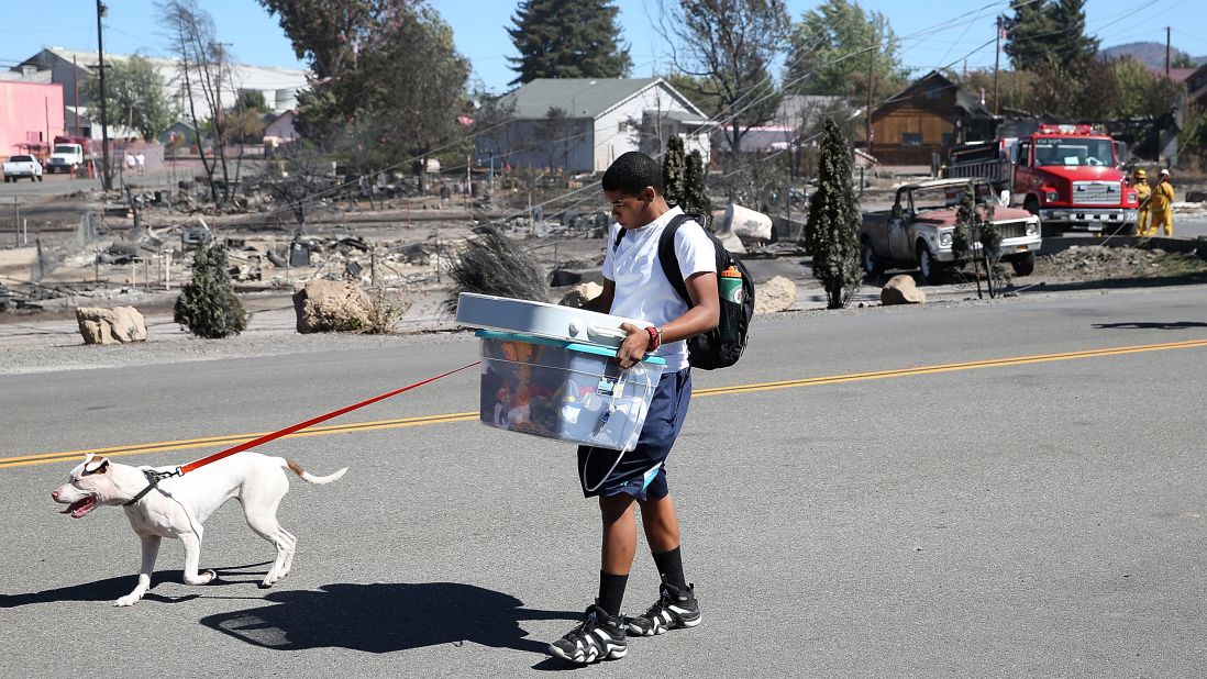 A resident of Weed carries belongings as he walks by burned-out homes on September 16.