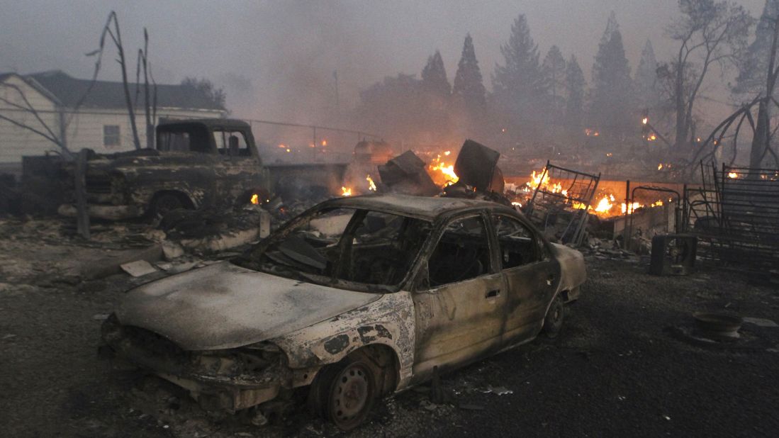 Destroyed vehicles and homes smolder in Weed on Monday, September 15.