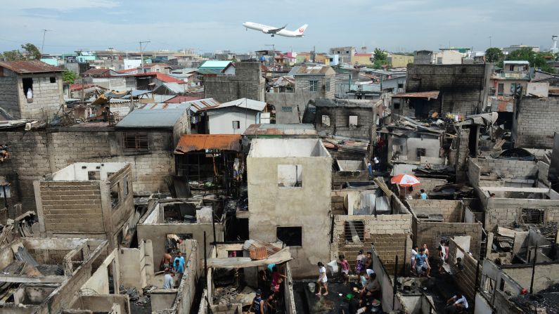 A Japan Airlines plane flies near burnt houses in Manila, Philippines, on Tuesday, September 16, after a fire gutted homes and left 750 residents homeless. 